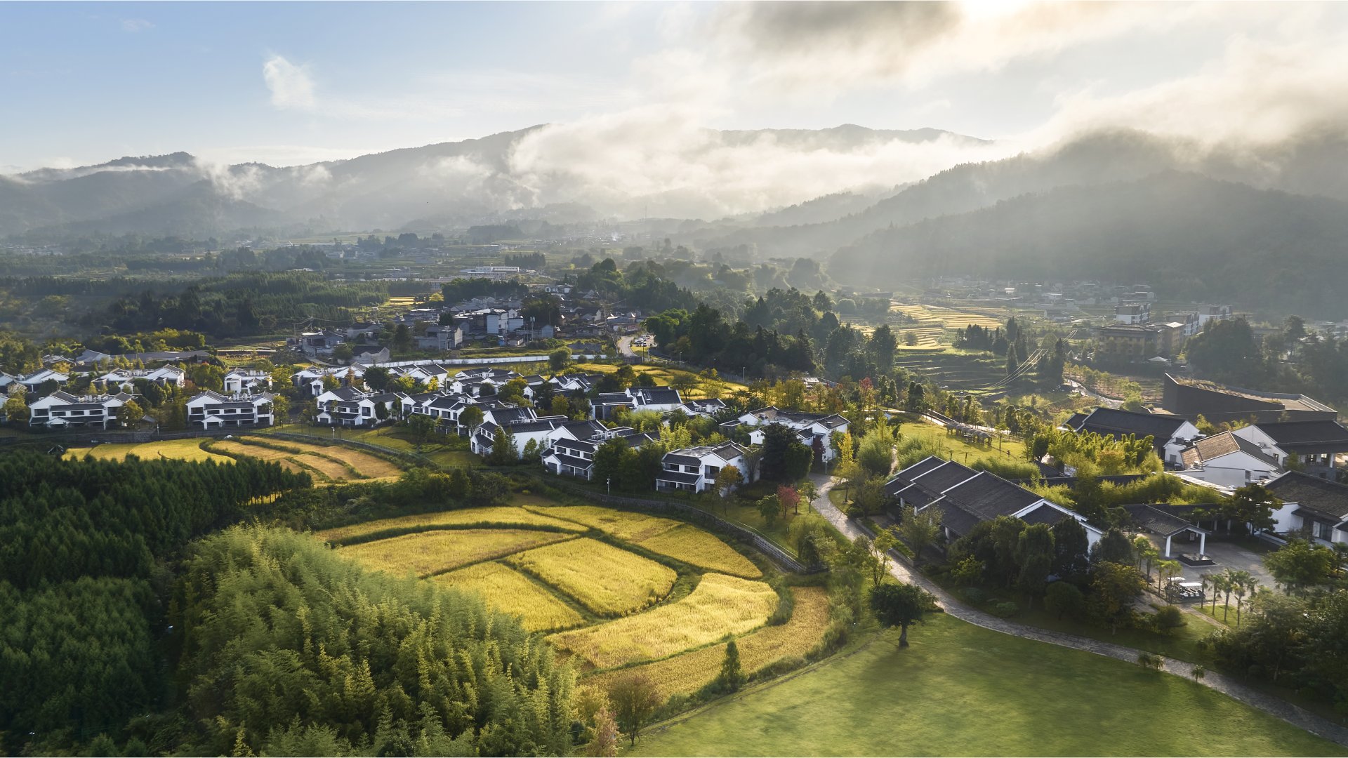 Aerial view of Angsana Tengchong China resort amidst lush greenery and misty mountains.
